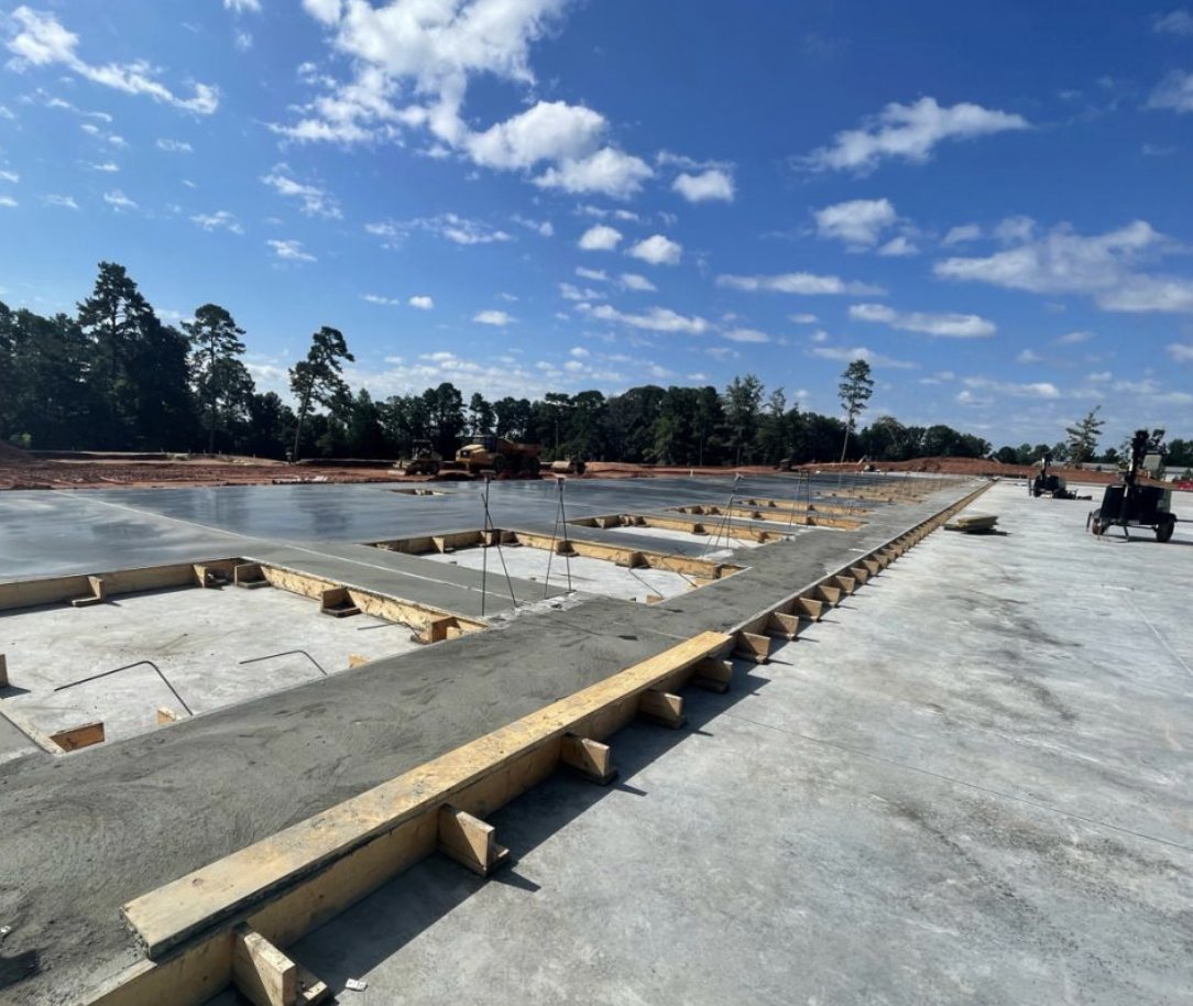 Freshly finished slab-on-grade pour with edge forms under a blue sky